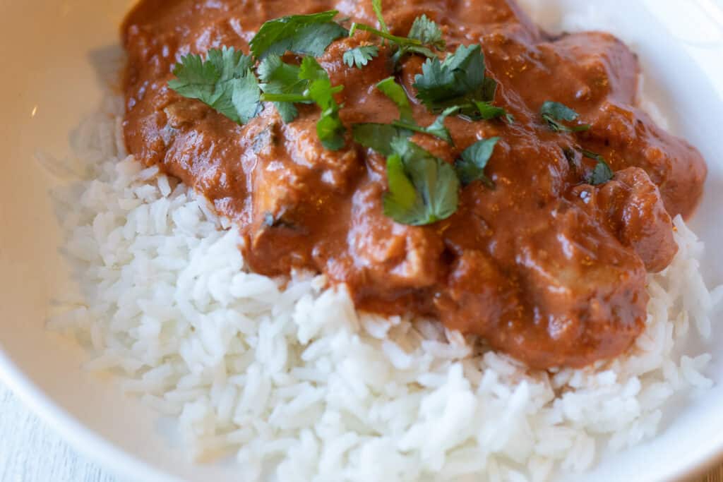 Plate of chicken tikka masala over rice with cilantro on top