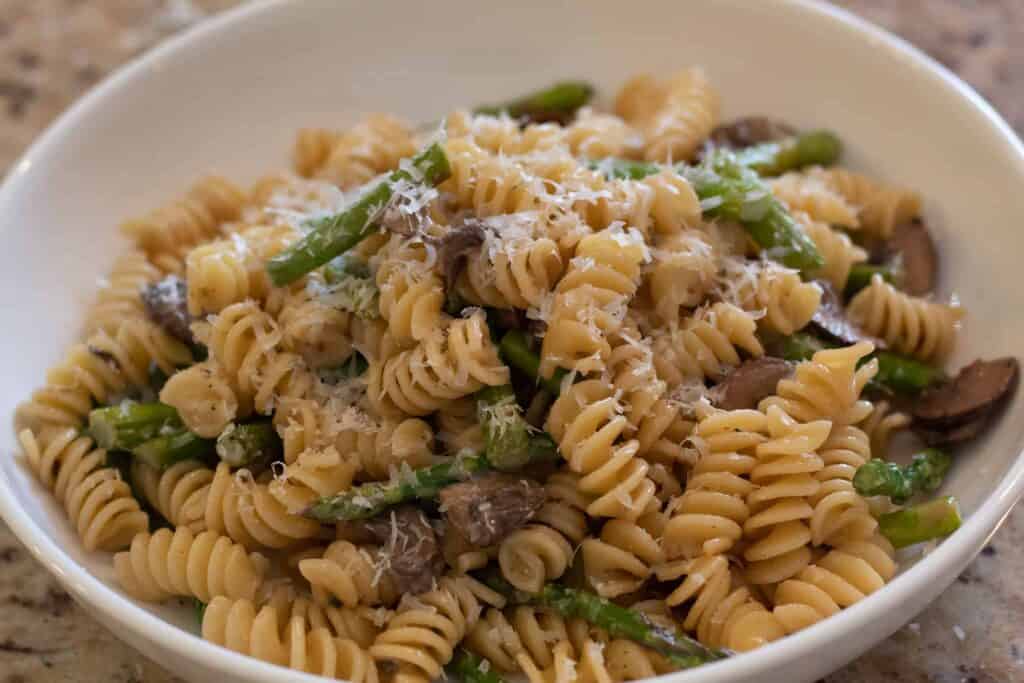 Bowl of rotini pasta with mushrooms and asparagus