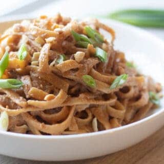 Bowl of Thai peanut noodles with sliced green onions