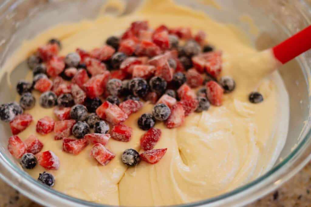 Bowl of cake batter with mixed berries ready to stir in
