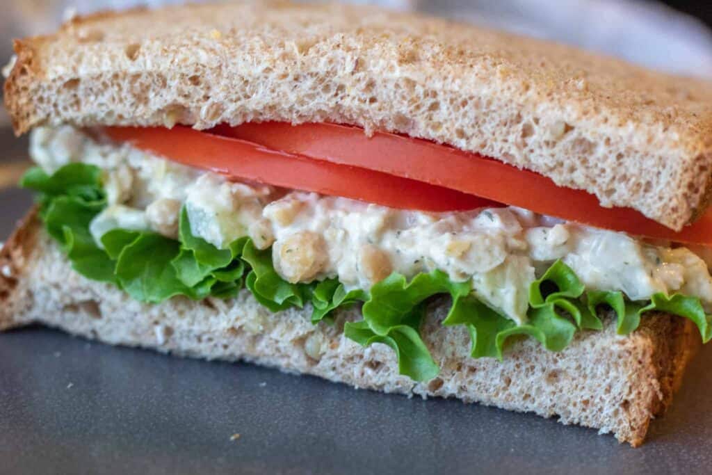 Creamy chickpea salad on a whole grain sandwich with lettuce and tomato
