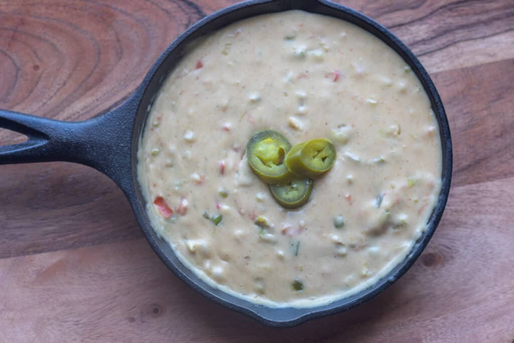 Queso in a cast iron pan with sliced jalapeños