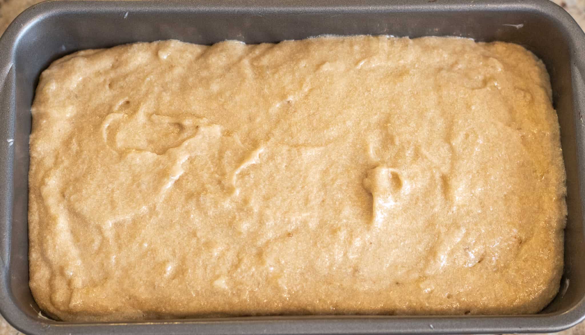 Uncooked banana bread batter in a metal loaf pan.
