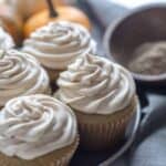Cupcakes next to a wood bowl with spices and pumpkins in the background