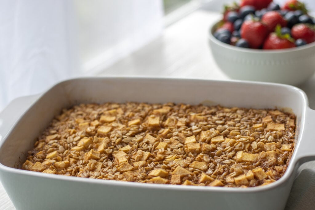 Baking dish with baked oatmeal and a bowl of blueberries and strawberries in the background