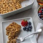 Plate of baked oatmeal with blueberries and strawberries, the baked oatmeal dish in the back