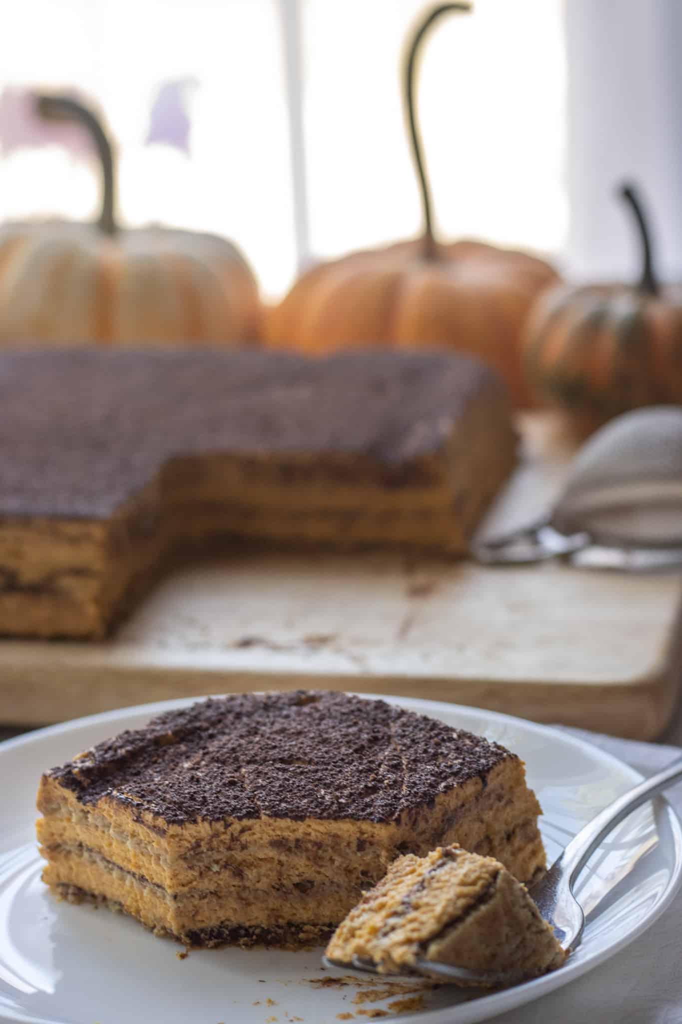 Upclose shot of a slice of pumpkin icebox cake with the cake in the background.