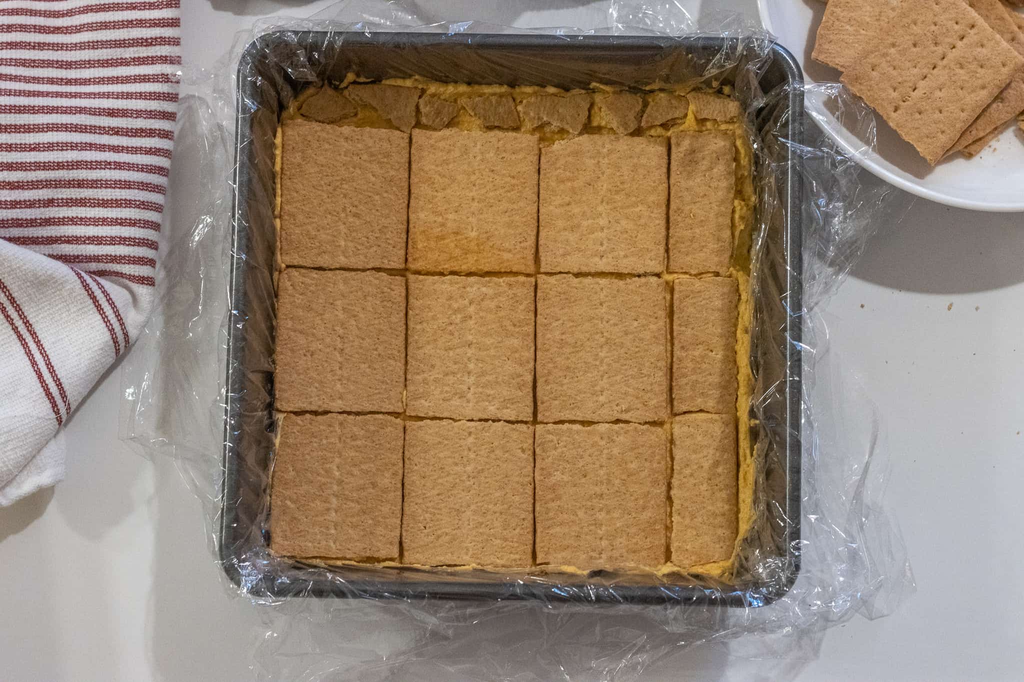 Plastic lined baking dish with a layer of graham crackers.