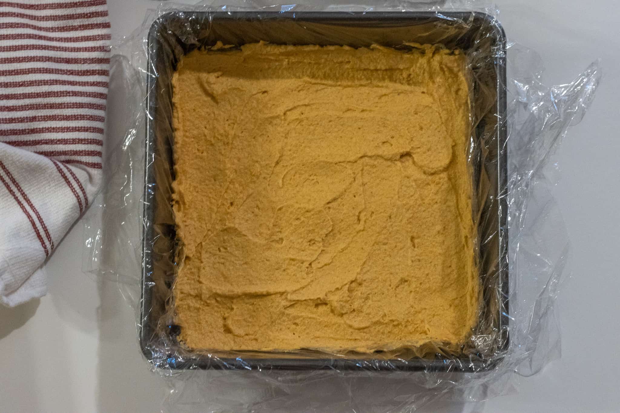 Plastic lined baking dish with a layer of whipped pumpkin filling.