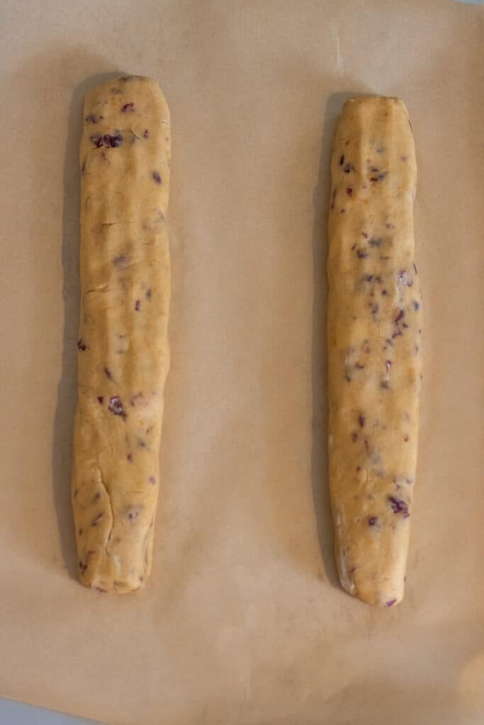 Raw biscotti dough formed into two logs on a parchment-lined baking sheet