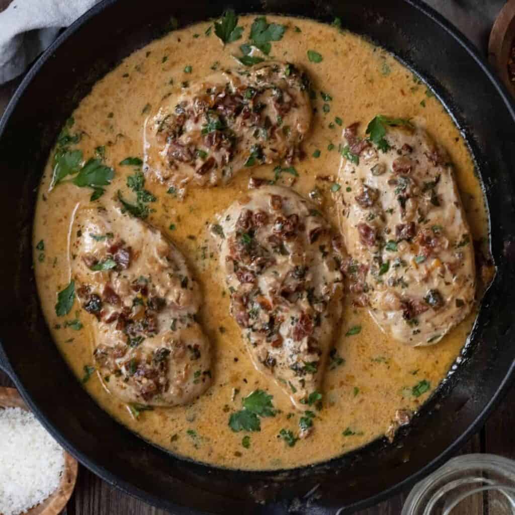 Pan with four chicken breasts in a creamy sundried tomato sauce