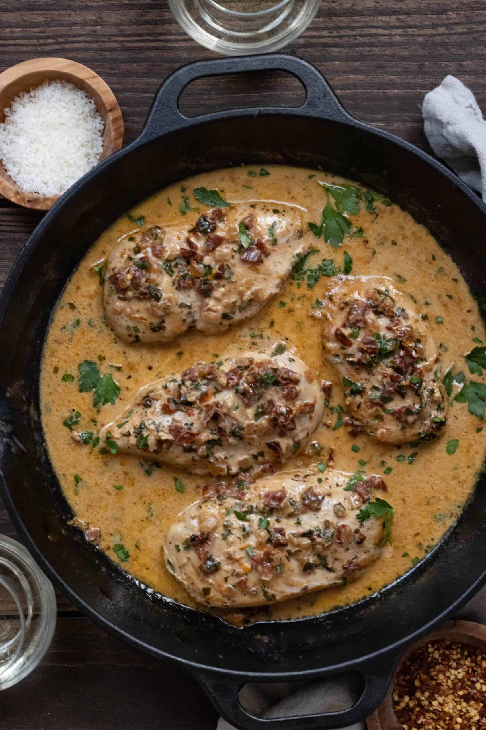 Cast iron skillet with four chicken breasts in a creamy sundried tomato sauce