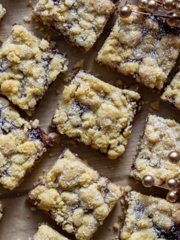 Sugar plum crumb bars cut into squares and spread out on parchment paper