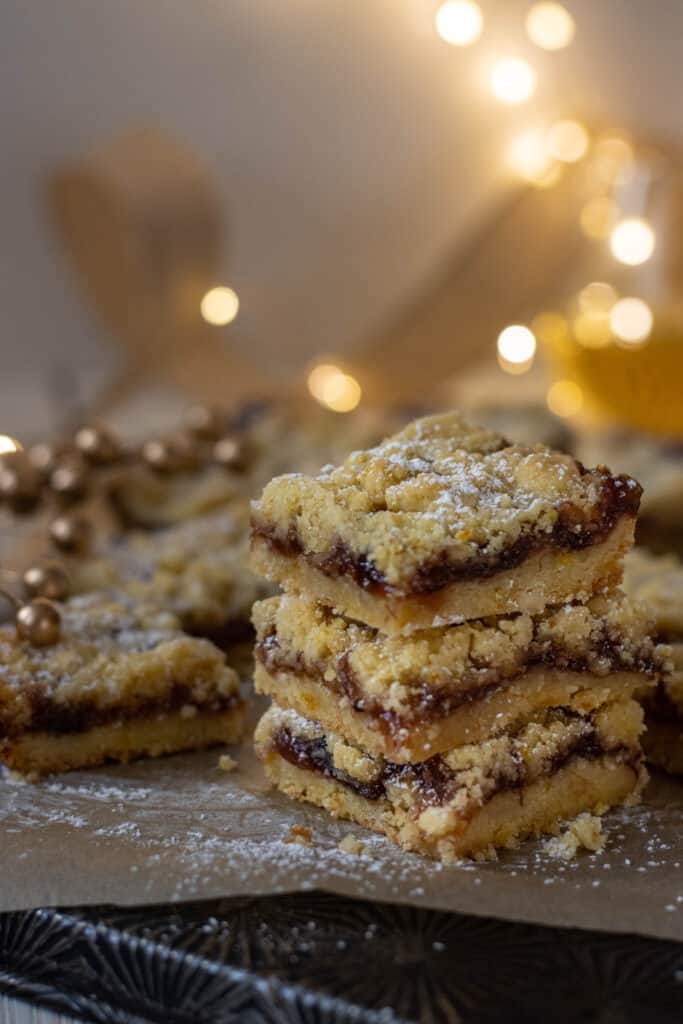 Stack of three crumb bars with more bars and fairy lights in the background