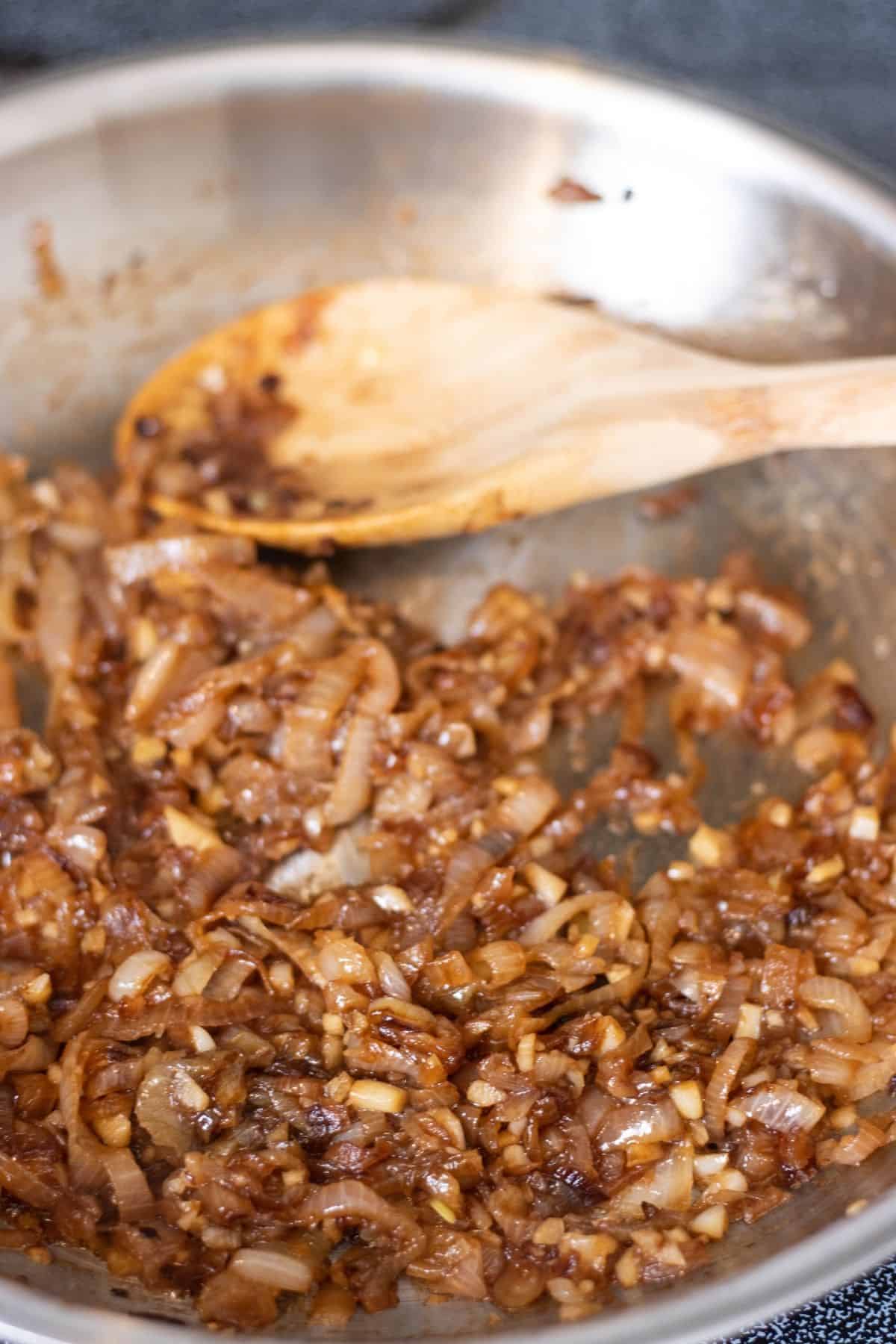 Caramelized shallots in a pan with a wooden spoon