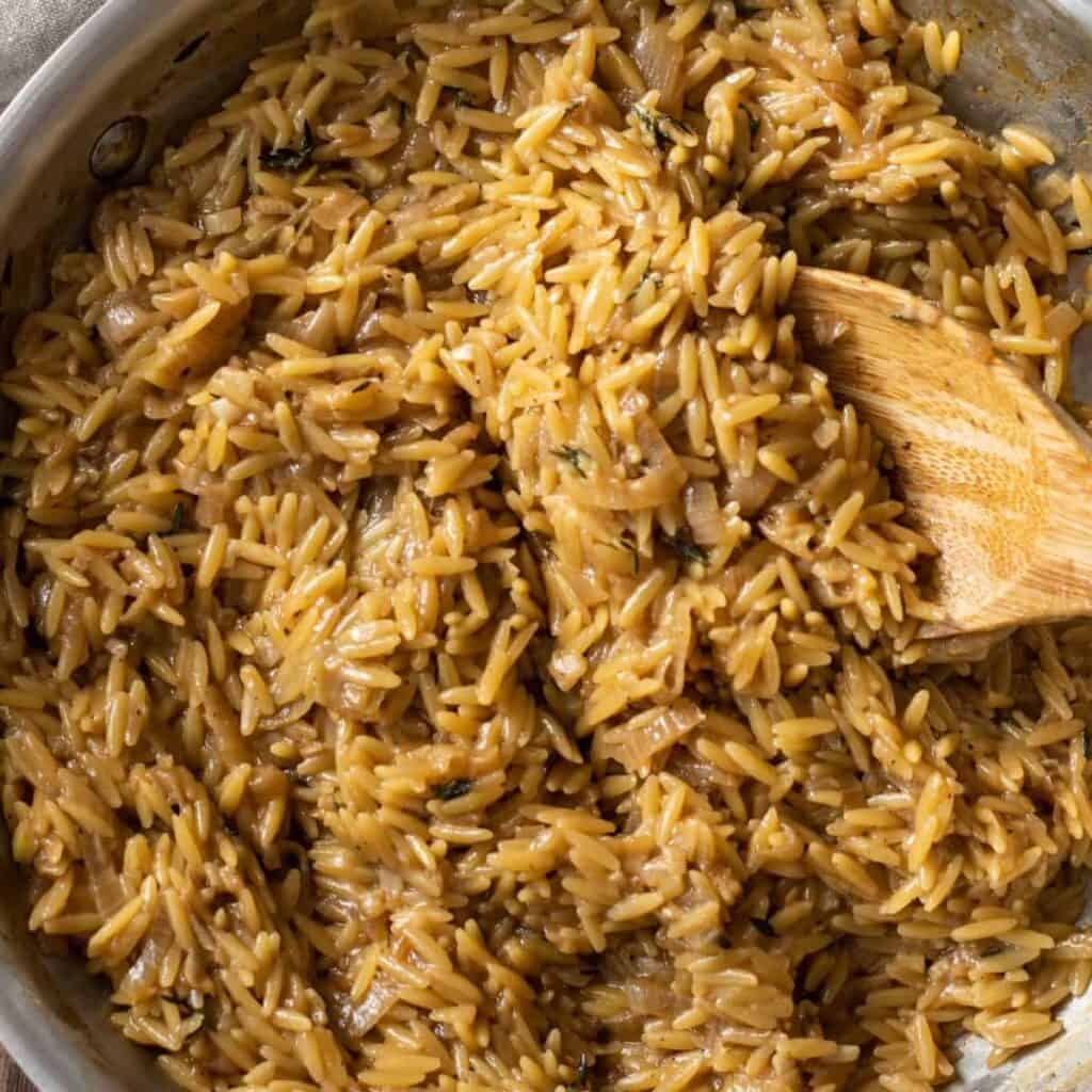 Garlic Parmesan Orzo in a steel pan with a wooden spoon