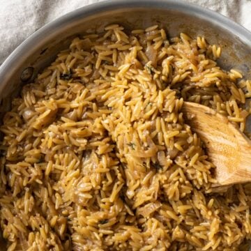 Pan with garlic parmesan orzo with a wooden spoon