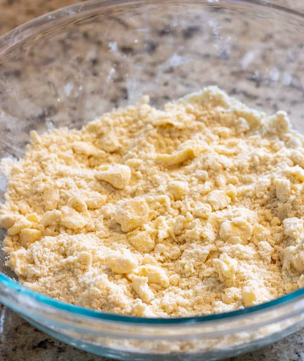 Chunks of butter coated in flour in a glass bowl.