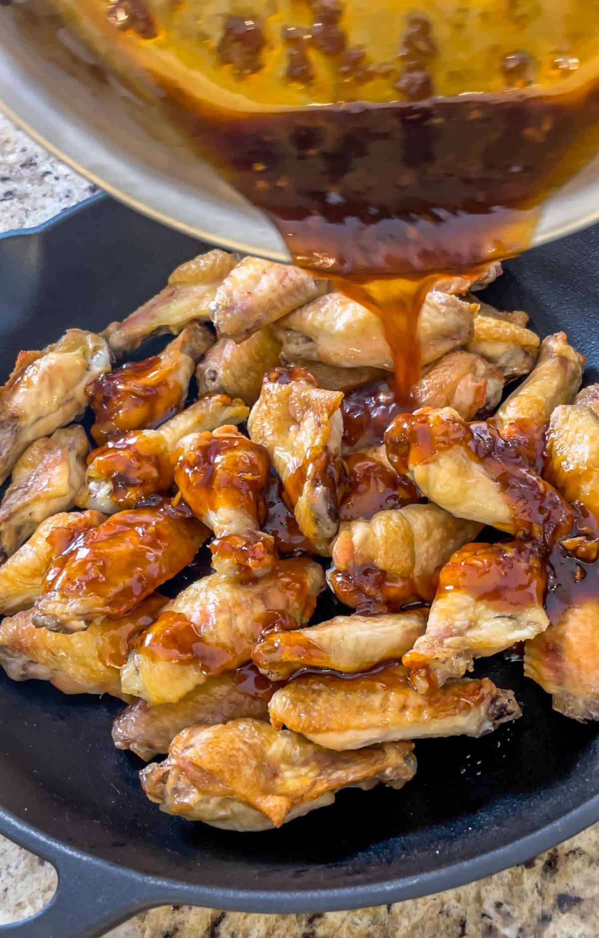 Honey sriracha sauce being poured onto wings.