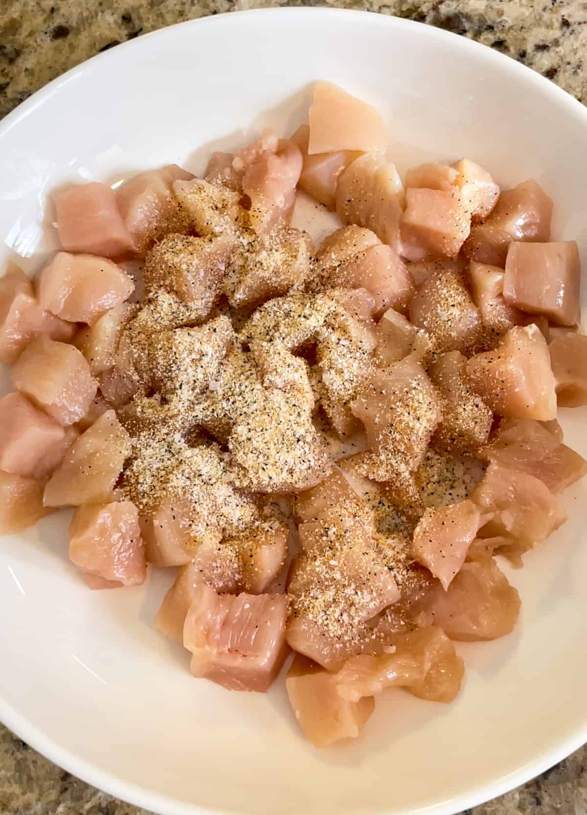 Diced chicken pieces topped with a seasoning mixture of garlic powder, salt, and pepper.