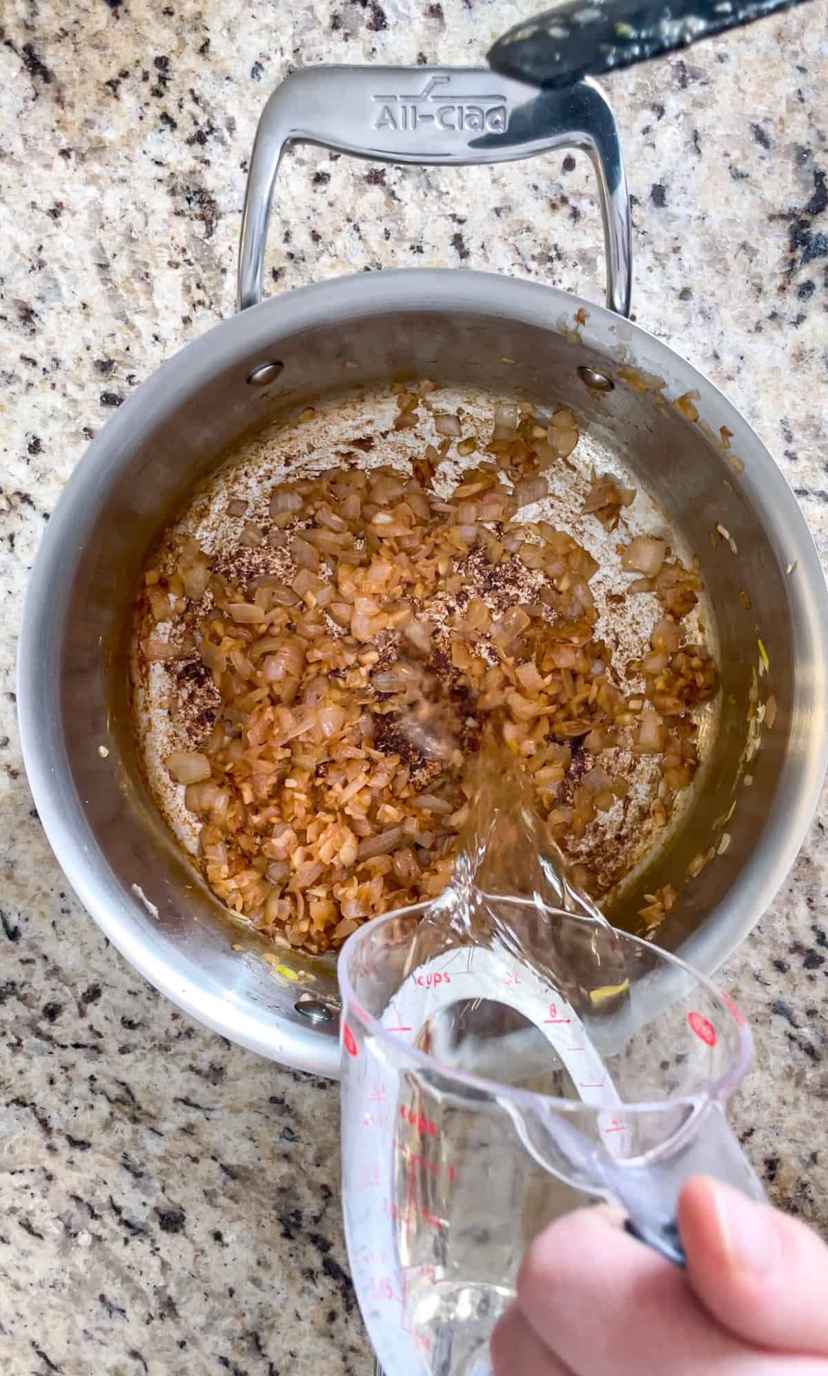 Champagne being poured into the caramelized shallots.