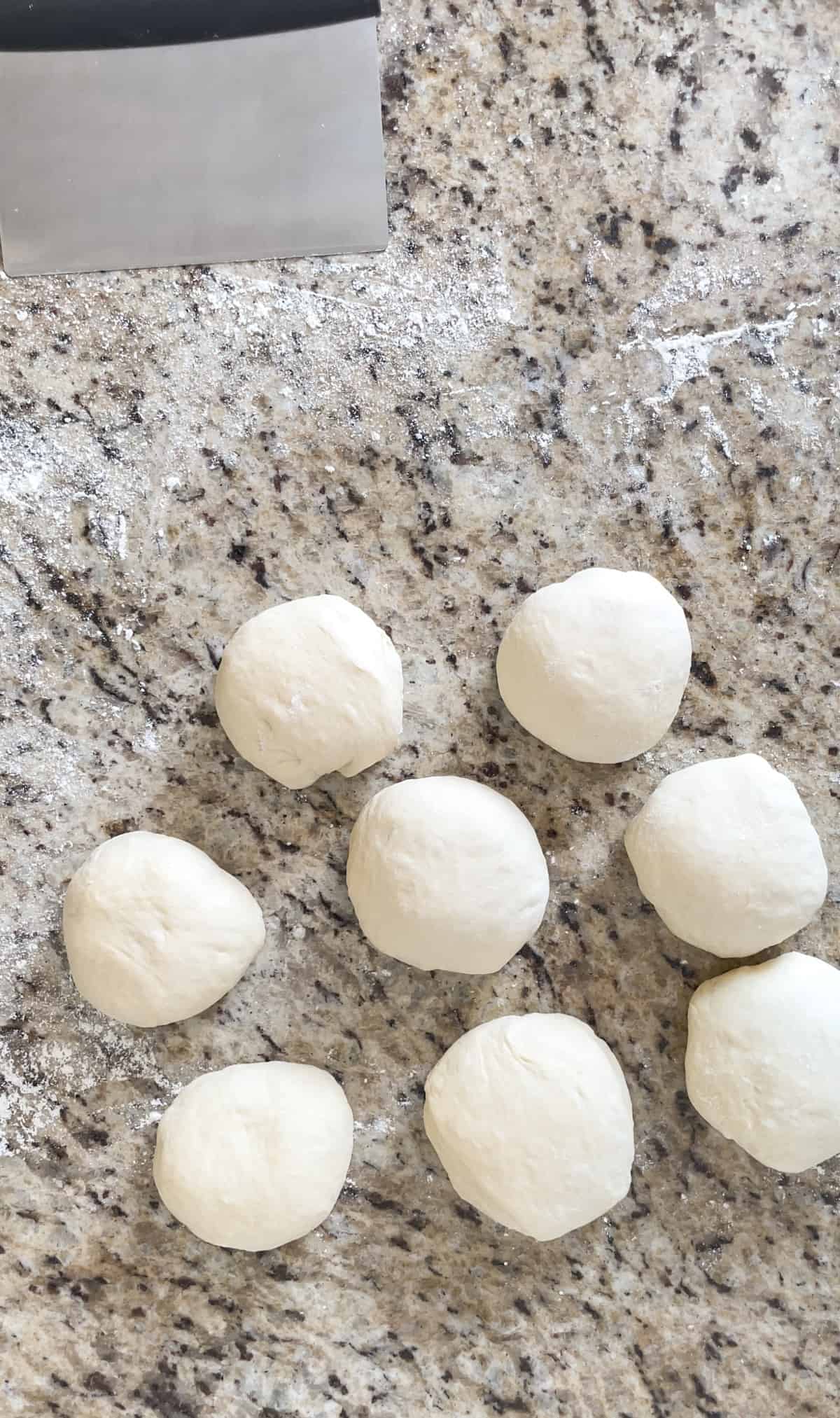 Eight pretzel dough balls on a counter.