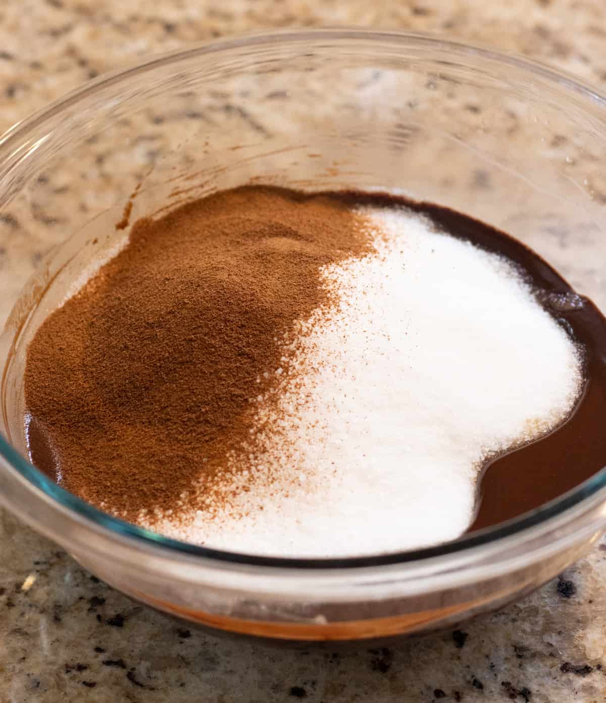 Sugar and espresso powder in a glass bowl with melted chocolate.