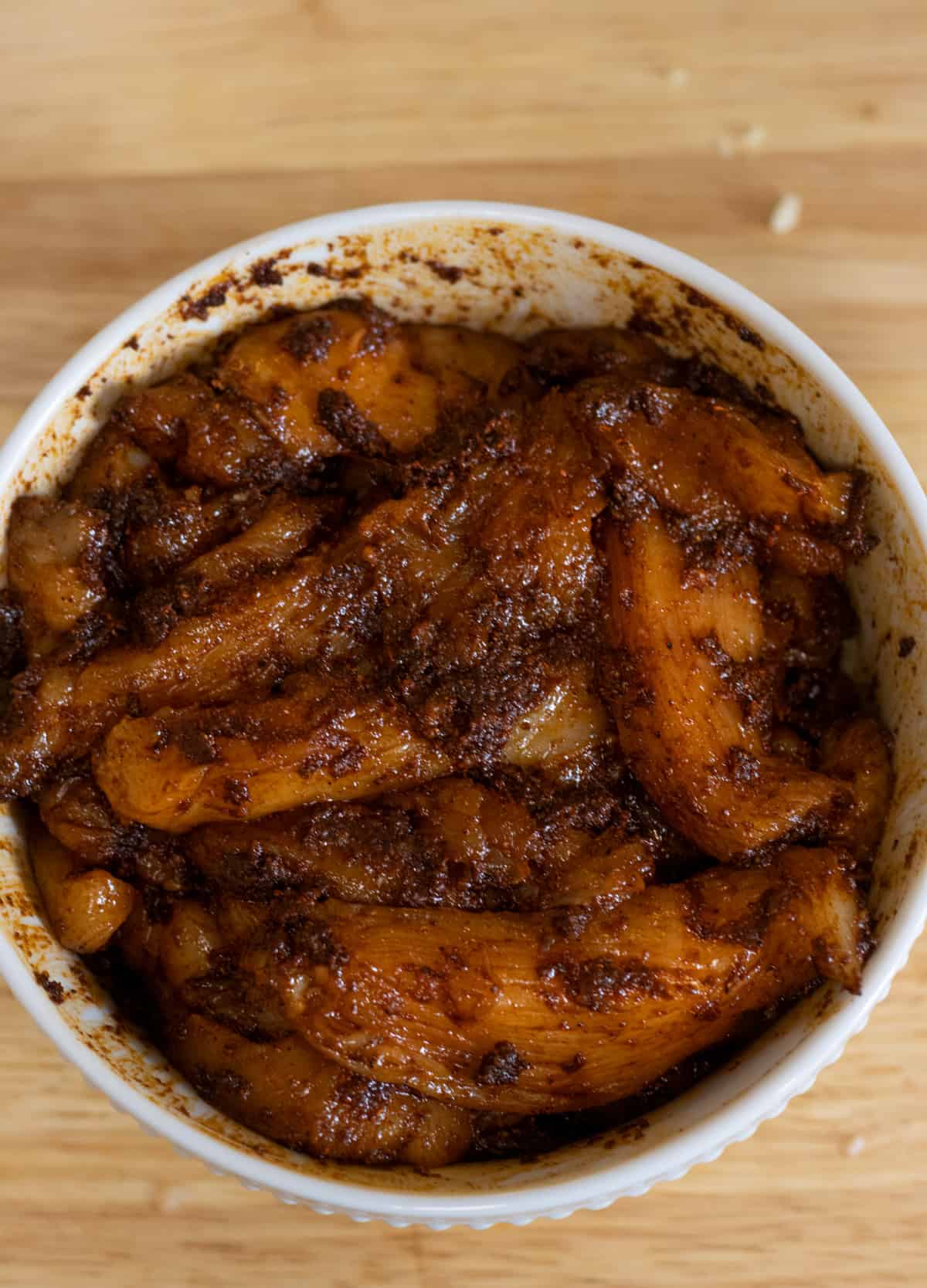 Sliced chicken tossed in adobo marinade in a bowl. 