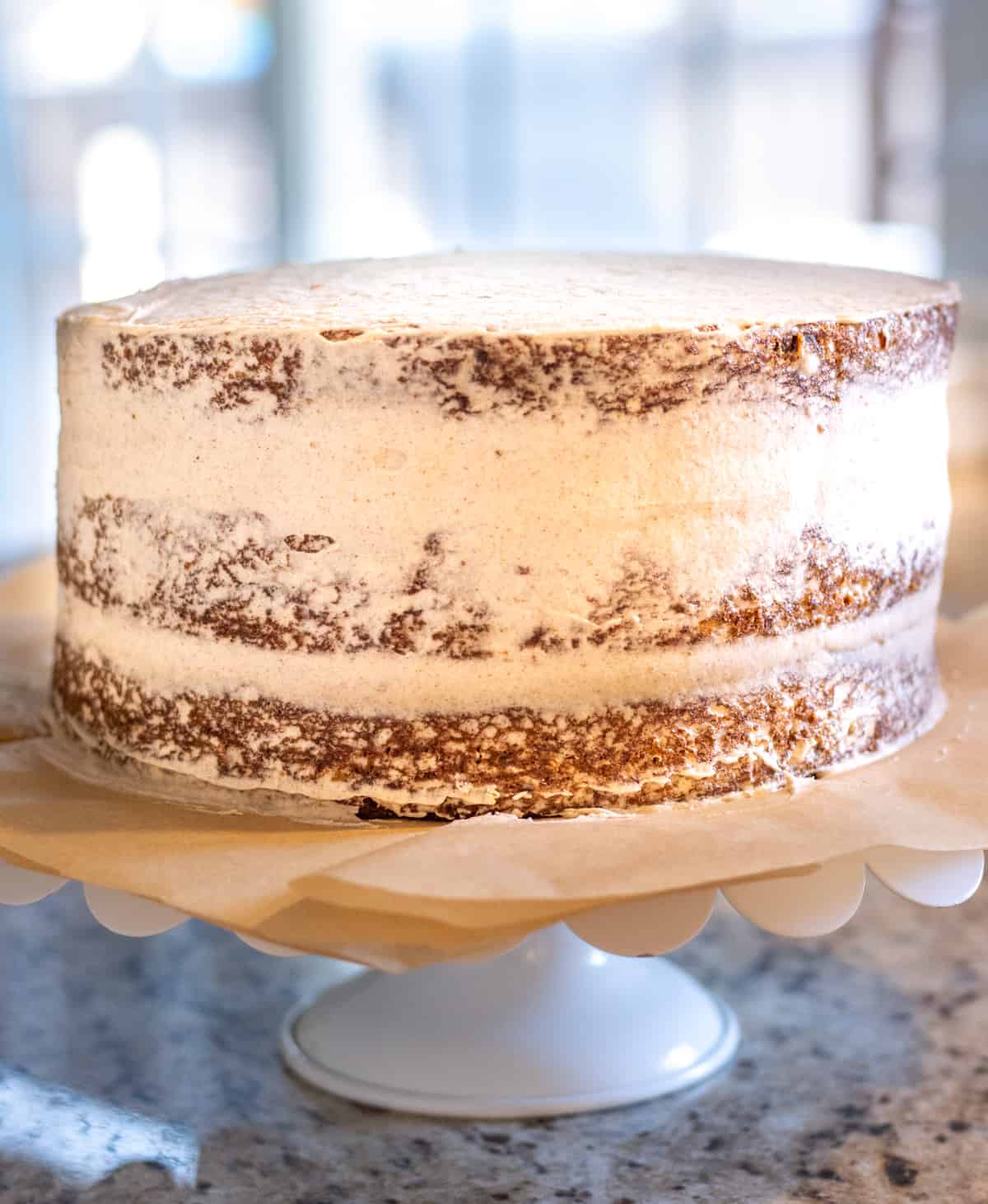 Three layer carrot cake with a crumb coating on a cake stand.