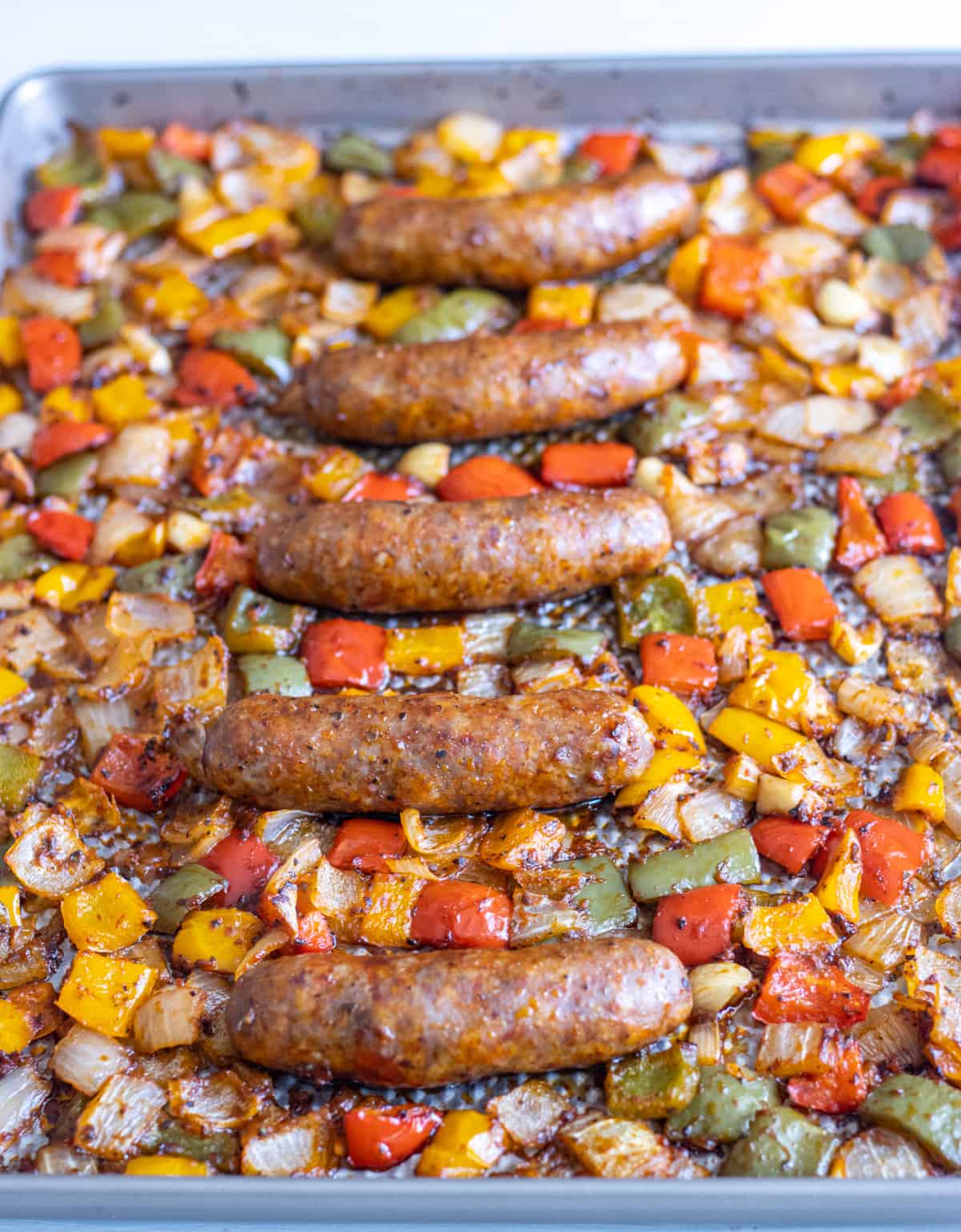 Italian sausages, peppers, and onions roasted on a sheet pan.