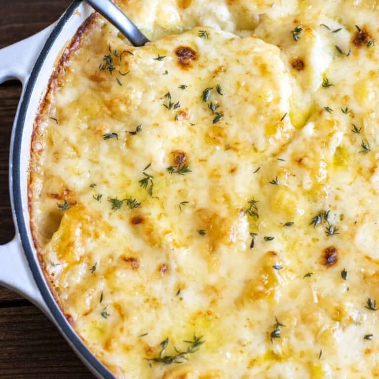Up close shot of potatoes au gratin in a baking dish with a spoon sticking out.