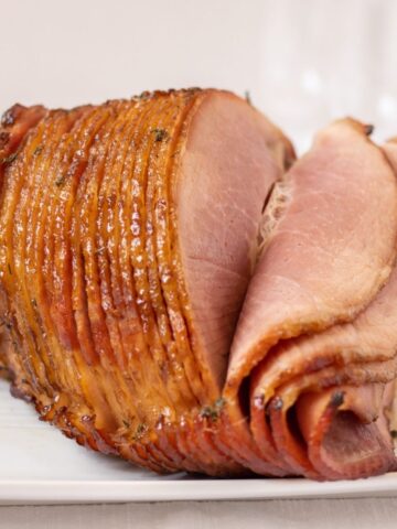 Spiral ham on a platter with some slices folded over.