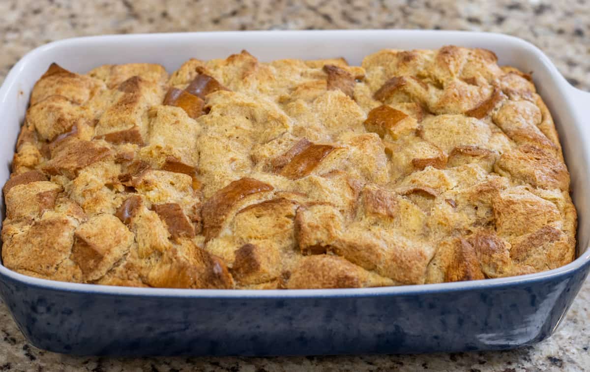 Brioche French toast casserole in a blue baking dish on a counter.