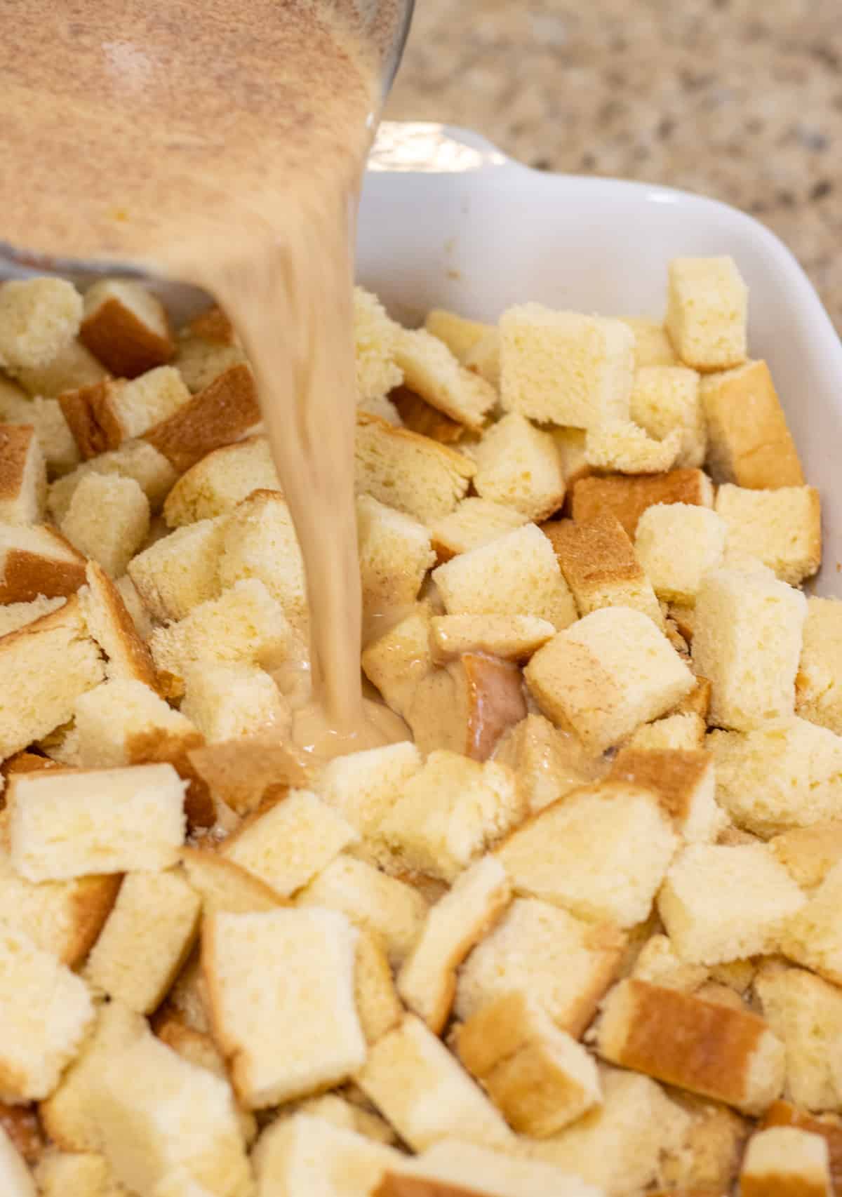 Custard being poured into bread cubes.