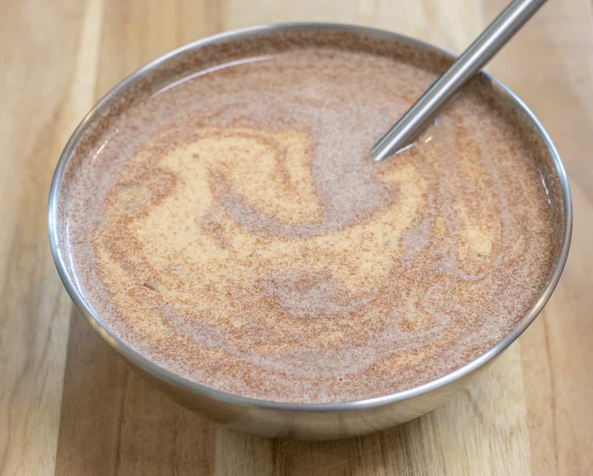 Egg custard in a metal bowl with a small whisk.