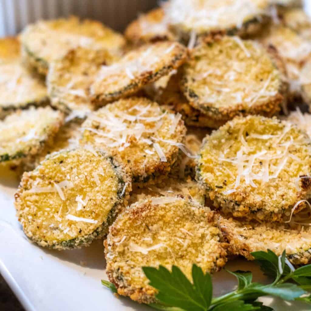 Breaded zucchini chips on a platter with parsley.