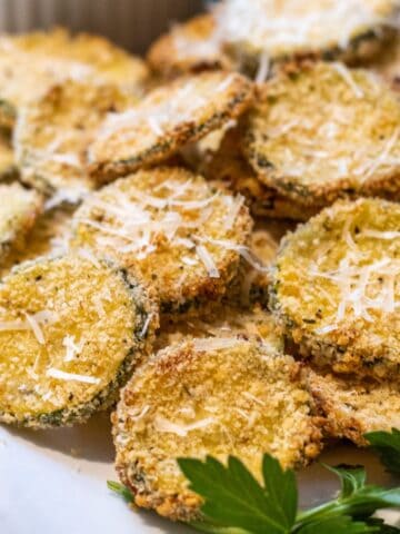 Breaded zucchini chips on a platter with parsley.