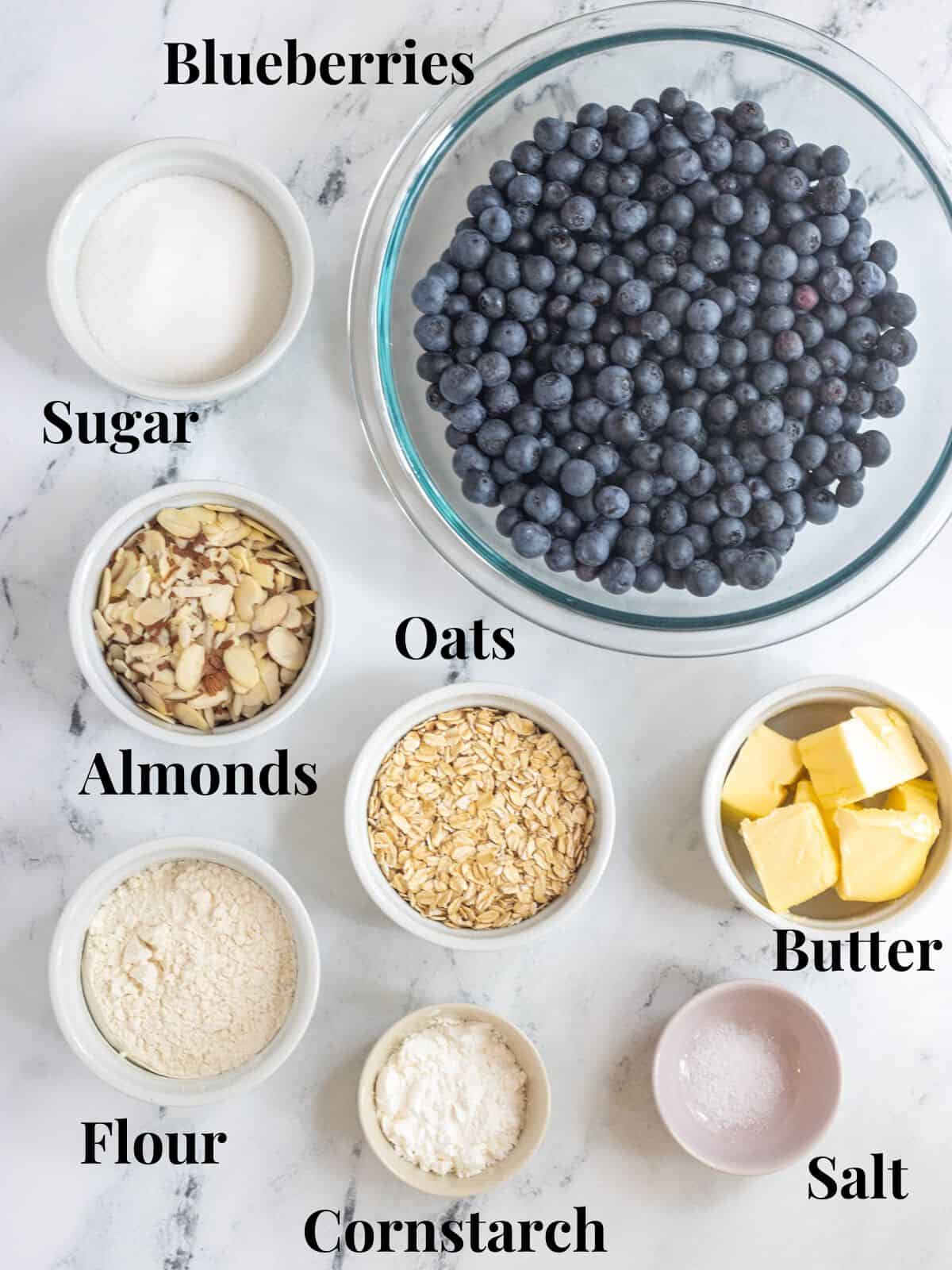Ingredients for blueberry crisp in bowls with labels.
