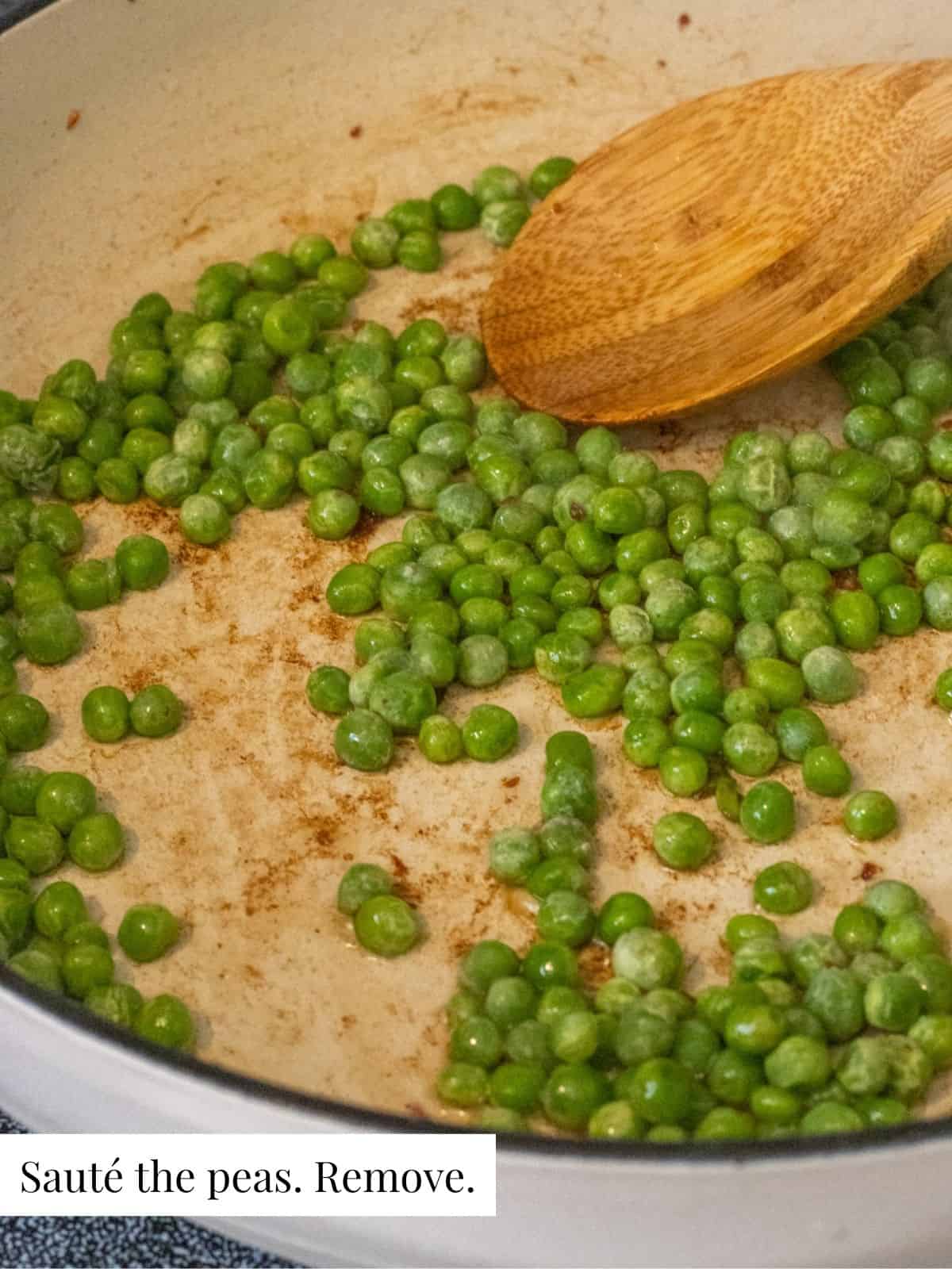 Peas sautéing in a pan with a wooden spoon.