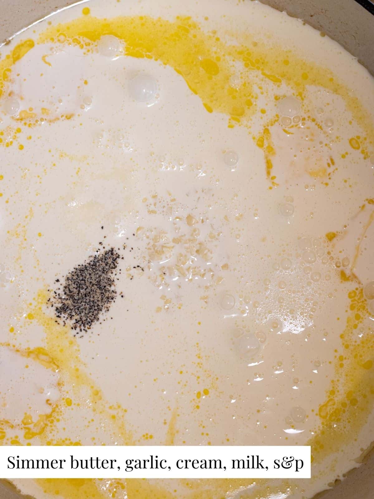 Melted butter, minced garlic, heavy cream, milk, salt, and pepper in a pan simmering.
