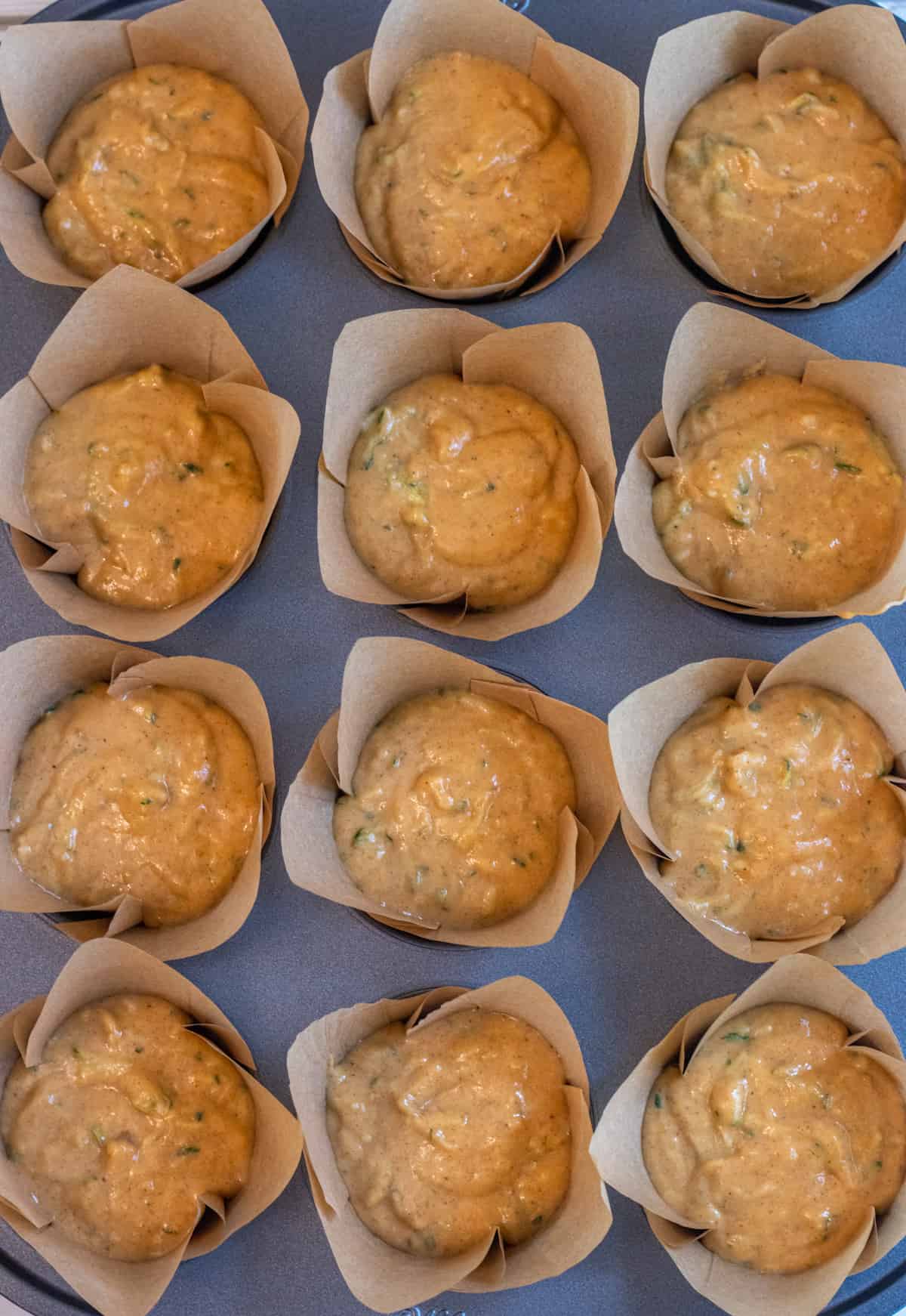 Tulip style muffin liners filled with pumpkin zucchini muffin batter.