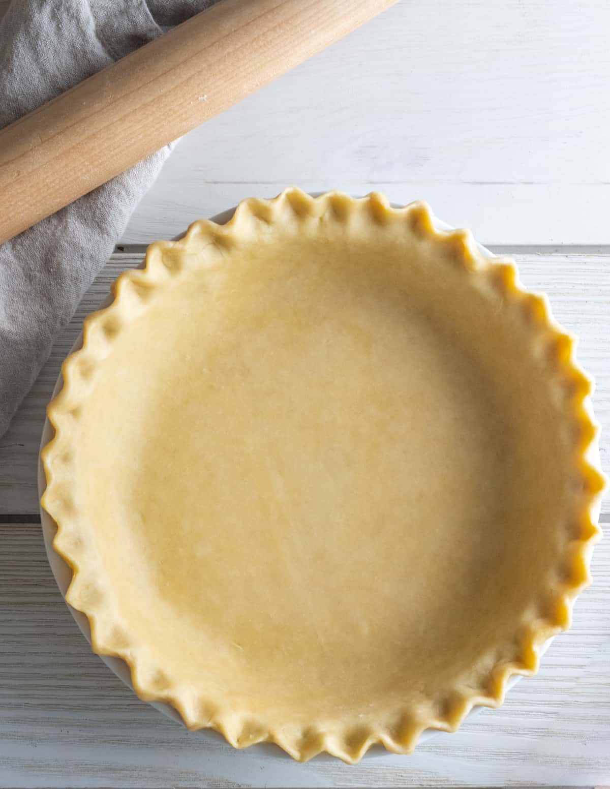 Overhead view of an unbaked pie crust with crimped edges in a pie plate.