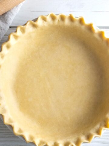 Overhead view of an unbaked pie crust with crimped edges in a pie plate.