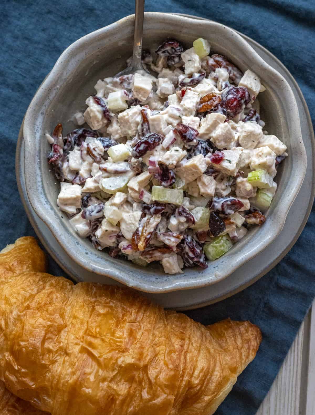 Cranberry pecan chicken salad in a bowl next to a croissant.