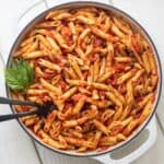 Pasta pomodoro in a large round casserole dish with basil leaves.