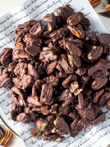 Chocolate covered pecans on a book page on a plate.