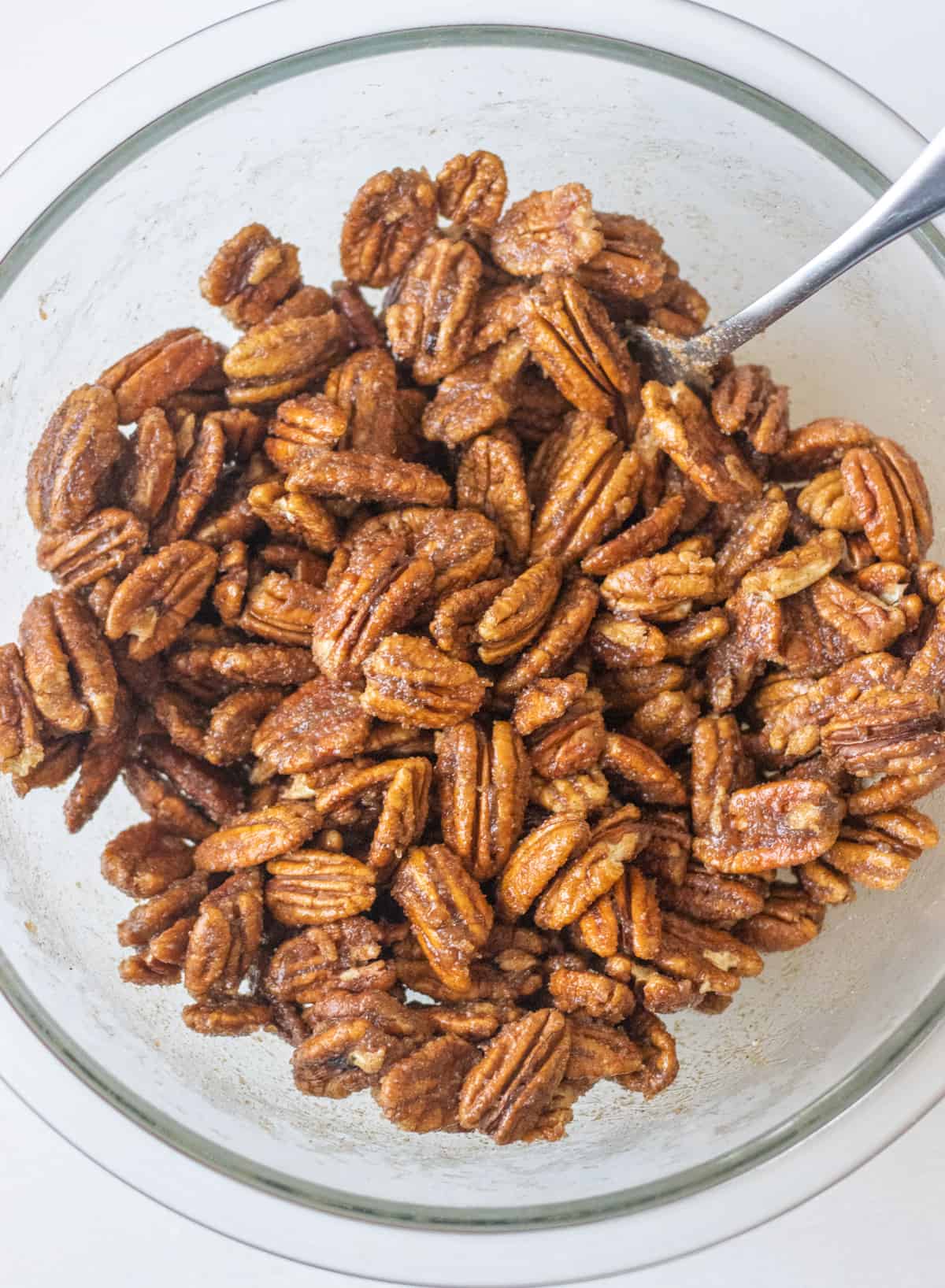 Pecan halves tossed in a brown sugar candy coating in a bowl.