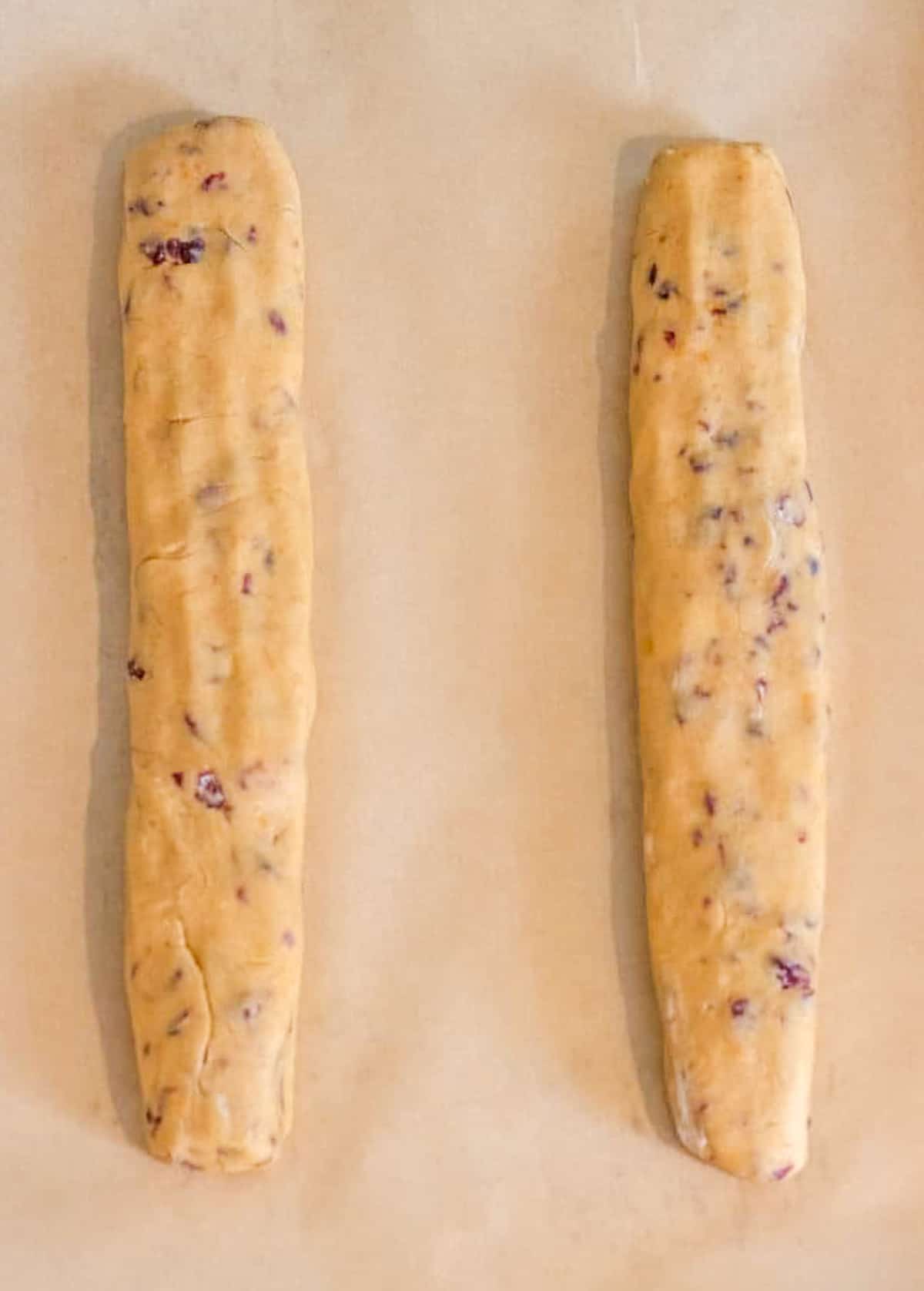 Two biscotti dough logs on parchment paper.