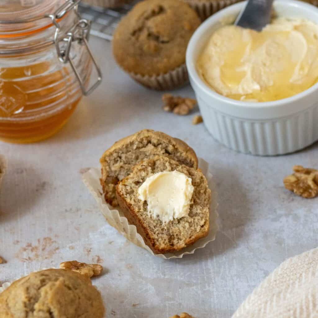 Banana walnut muffin cut in half with a smear of honey butter.