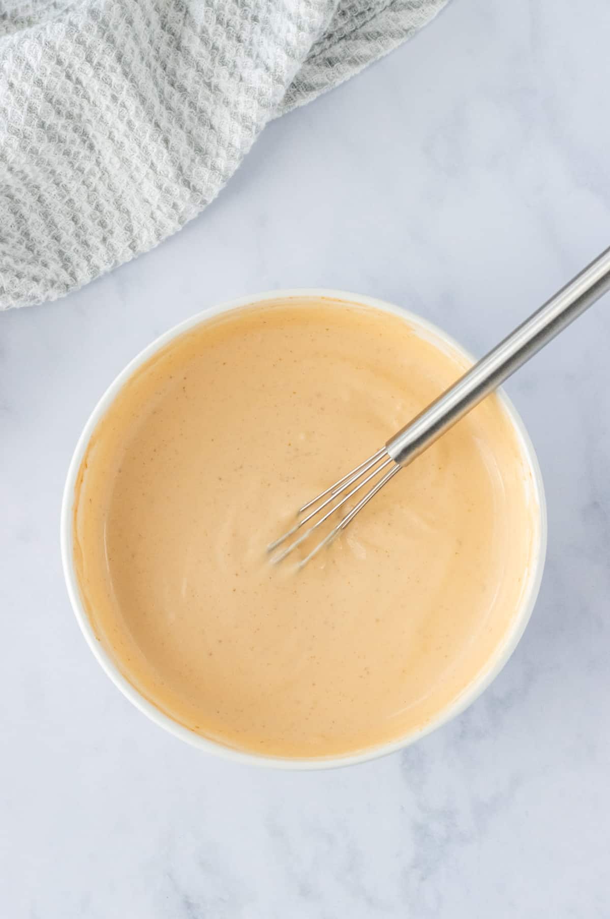 Sriracha Aioli in a bowl with a whisk.